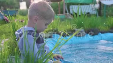 那个男孩坐在一个小湖边。 这孩子用脚造成水溅. <strong>夏日炎炎</strong>。 快乐的童年